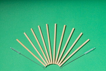 Bamboo cocktail straws and cleaning brush on green background. Bamboo drinking straws. Eco friendly lifestyle. Zero waste concept