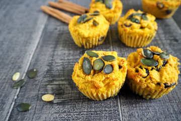 four gluten-free pumpkin muffins, sprinkled with pumpkin seeds, lie on a wooden table. side view. vegan gluten-free meringue sweets, lactose-free