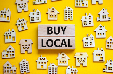 Buy local and house symbol. Concept words 'Buy local' on wooden blocks near miniature houses....