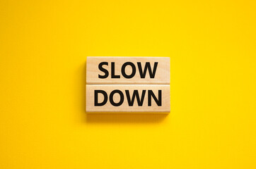 Time to slow down symbol. Concept words Slow down on wooden blocks on a beautiful yellow background. Business and slow down concept. Copy space.