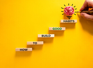 Build good habits symbol. Wooden blocks on beautiful yellowbackground, copy space. Words 'How to build good habits'. Businessman hand, light bulb. Build good habits concept. Copy space.