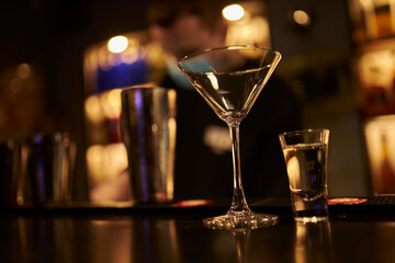 Martini glass and shot glass are on the bar. 