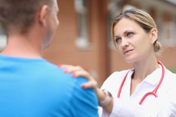 Woman doctor putting hand on patient shoulder to calm down