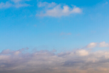 A blue sky background with thick clouds at the bottom and one light air cloud at the top. Clear weather after giving