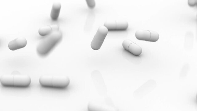 In front of the camera, the white capsules of the medicine fall onto a shiny white surface, turn over and stop. This is a medicine for the Paxlovid coronavirus. Bokeh effect.