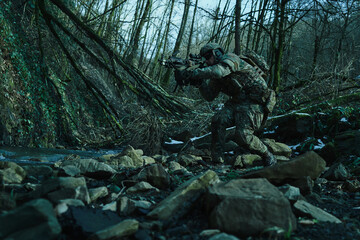 Portrait of airsoft player in professional equipment with machine gun in the forest. Soldier with weapons at war