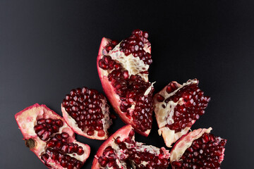 Red ripe fresh juicy sliced pomegranate isolated on black background