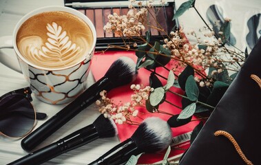 Cup of coffee, eyeshadow palette and glasses on white wood background in summer