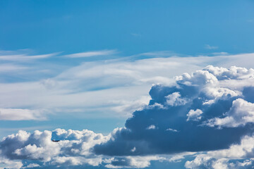 silhouette of a flying plane against the background of cumulus clouds
