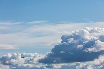 silhouette of a flying plane against the background of cumulus clouds
