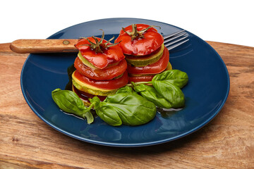 Baked tomatoes and zucchini with basil on a blue plate