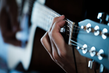 Hand playing on a guitar.