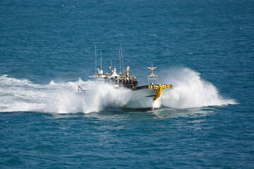 The fishing boat in sea splashes, floats with high speed.