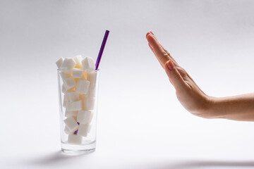 Stop sugar! A full glass of sugar and a woman's hand with a refusal gesture. The concept of...