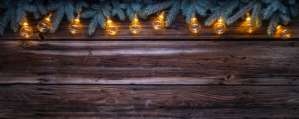 Cozy copy space background with spruce branches and Christmas string lights on barn wood