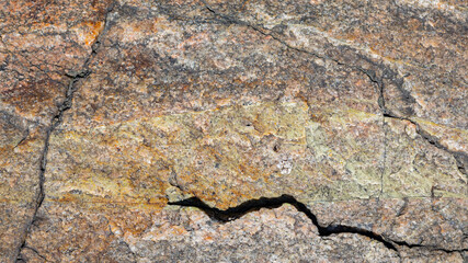 Texture of granite rock. Cracked stone surface from weathering. Close up of granite surface. Earth color concept