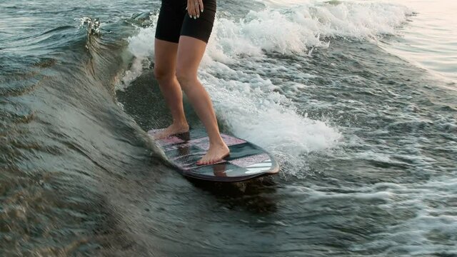 A female surfer jumping on a wakeboard. An experienced wakeboarder splashes water drops into the camera.