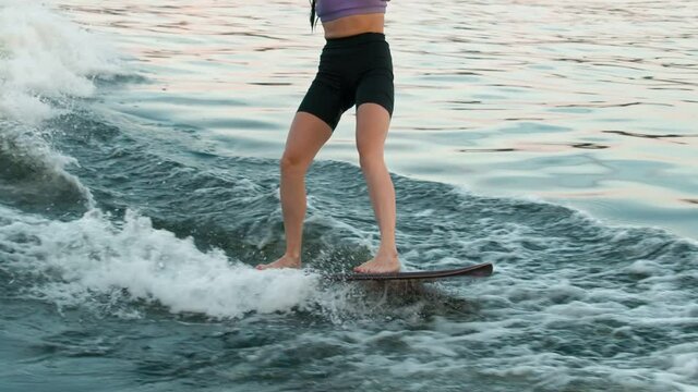 A female surfer jumping on a wakeboard. An experienced wakeboarder splashes water drops into the camera.
