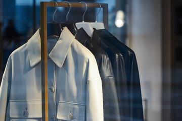 Leather jackets of white and black color hang on the hanger in a row.