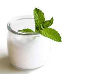 A glass jar with a moisturizer or balm. Top with a sprig of mint. Space for text. Concept: cosmetology, spa, body care, vitamins, medicine, diet, healthy food.