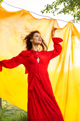 pretty woman in red dress yellow fabric on nature background