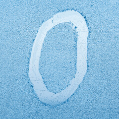 The letter O written on glass with frost in the frost in winter, close up
