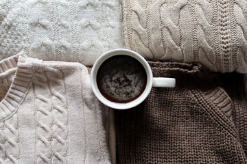 Fototapeta na wymiar Cup of black coffee on woolen sweaters background at home. Close up, selective focus and copy space