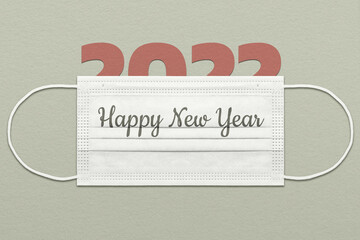 The greeting card concept with the number 2022 under a medical mask with the inscription "Happy New Year"