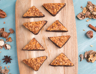 Nut corner, traditional german sweets called Nussecke, covered with chocolate, christmas baking, blue textured background