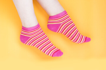 A pair of textile thin colorful striped socks on women's legs.