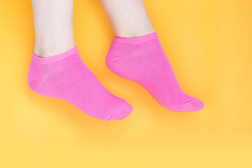 Woman dressed in bright pink socks on a yellow background