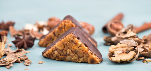 Nut corner, traditional german sweets called Nussecke, covered with chocolate, christmas baking, blue textured background