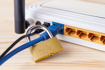 Close-up of metal padlock locked blue network cable of white Wi-Fi wireless router on a white...