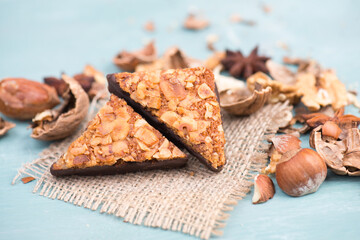 Nut corner, traditional german sweets called Nussecke, covered with chocolate, christmas baking, blue textured background