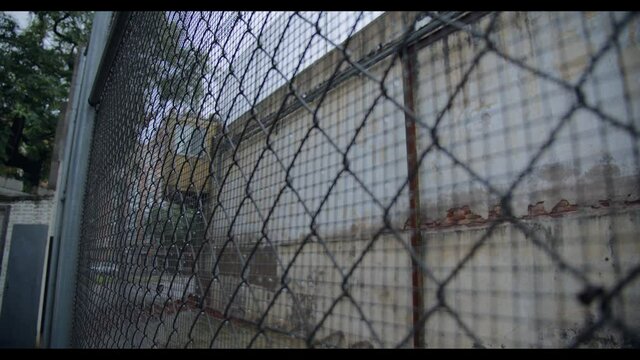 A look through the chain-link fence of the prison or restricted facility with raindrops on a cloudy and rainy day. Hopeless and depression concept.