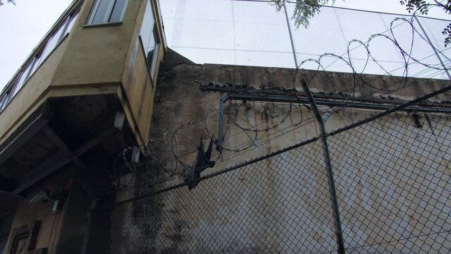 Old scraps of prisoner robe on the barbed wire of the prison.  A prisoner escaped the prison without being detected by an outdoor surveillance camera.