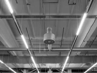 Ventilation and air conditioning system in industrial or commercial premises with lighting, under the ceiling. Ventilation pipes and hoods. Monochrome, symmetry, black and white image.