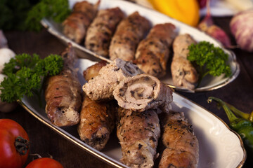 Pork rolls with mushrooms, meat rolls surrounded by greenery and vegetables. Ukrainian dishes is called krucheniki