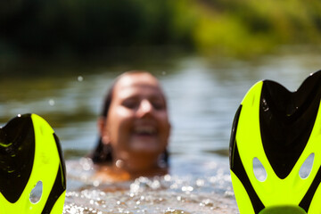 Young woman in bikini going to snorkeling in a sea. Slim caucasian girl holds mask and flippers at the seashore