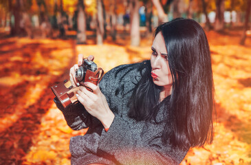 Young woman photographs with vintage film camera. An old film camera in female hands. Woman taking...
