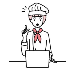 デスクで座ってPCを開いて何かひらめいた調理師の女性