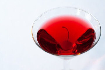 An isolated image of a martini glass with red liquid and a cherry inside on a white background.  Image contains copy space.