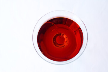 An isolated image of a martini glass with red liquid and a cherry inside on a white background.  Image contains copy space.