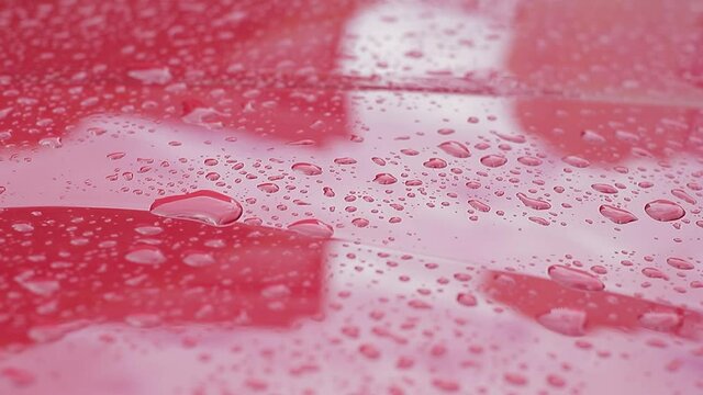 Gotas de agua cayendo sobre el capó de un auto. Video en camare lenta.