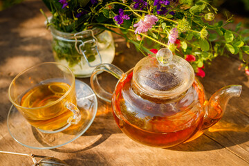 Summer healthy herbal tea in a glass teapot and bunches of medicinal herbs on wooden board. . Phytotherapy. Herbal medicine.