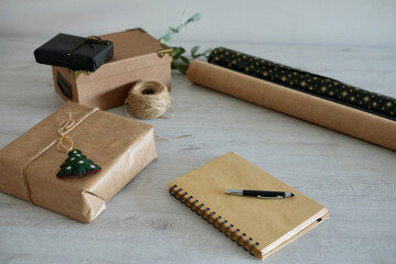 Office desk table with blank notebook to jot down Christmas to-do list with pen, laptop, paper and Christmas gift. Top view with copy space, flat lay.