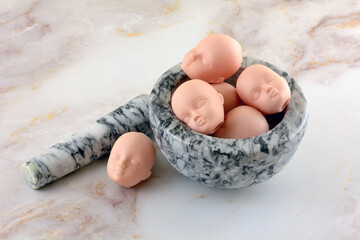 Doll heads in and next to granite mortar and pestle for horror or Halloween decoration