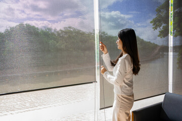 Happy asian woman relax with green nature through the glass window in home. Asian girl open the...