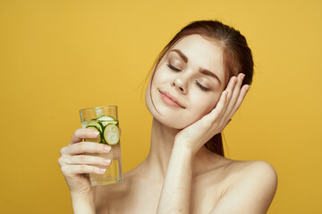 woman with cucumber drink vitamins body care yellow background