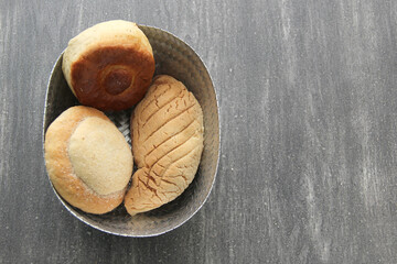 Mexican sweet bread such as biscuit, croissant, grating and fluffy worm, fresh, freshly made at home on a wooden table with napkin and basket
